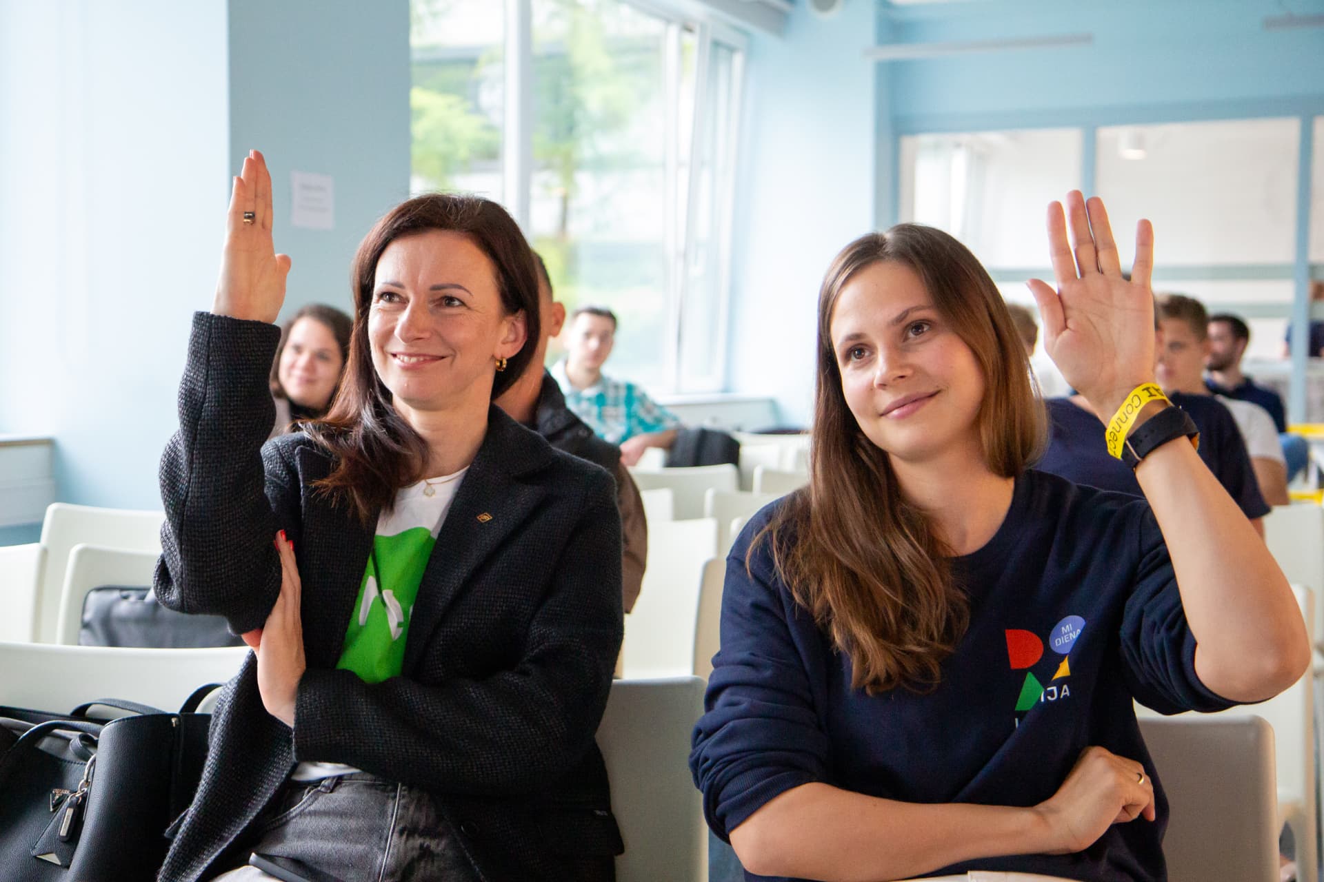 Two attendees raising their hands during a session